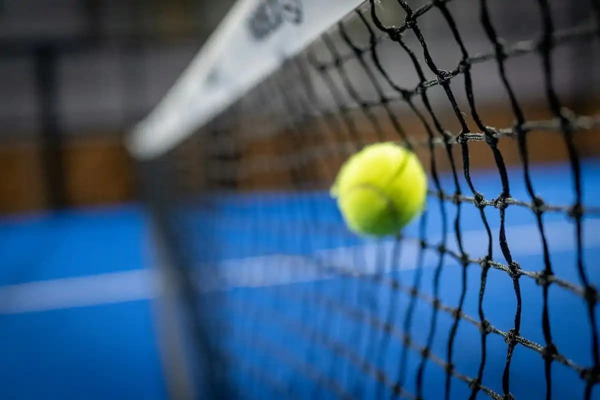 Photo of a padel court net and ball during game play.